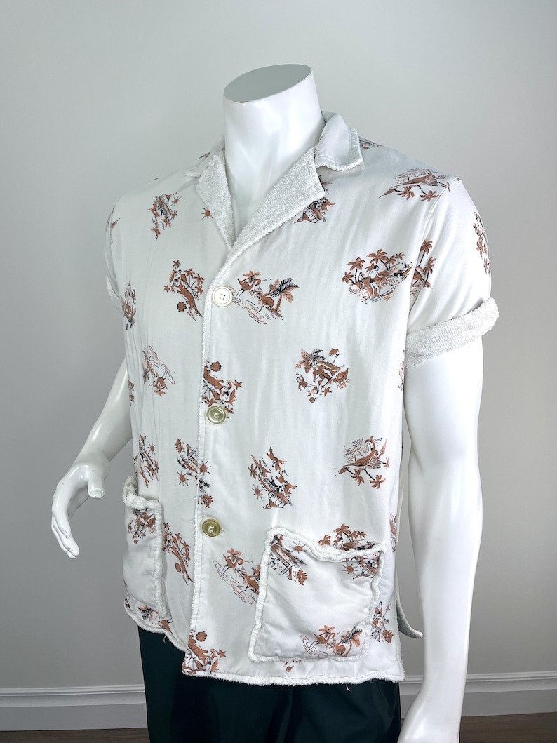 May include: White short-sleeved shirt with a brown and tan tropical print. The shirt has two front pockets, a collar, and two buttons. The cuffs and collar are trimmed with a white terry cloth material. The shirt is displayed on a white mannequin.