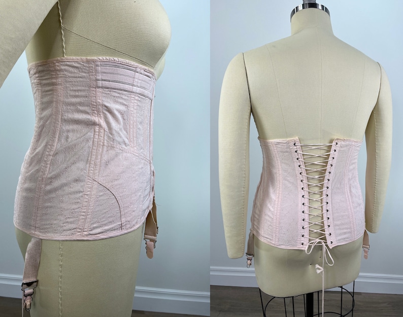 May include: A pale pink corset with a lace-up back and garter straps. The corset is made of a soft, lightweight fabric and has a vintage style.