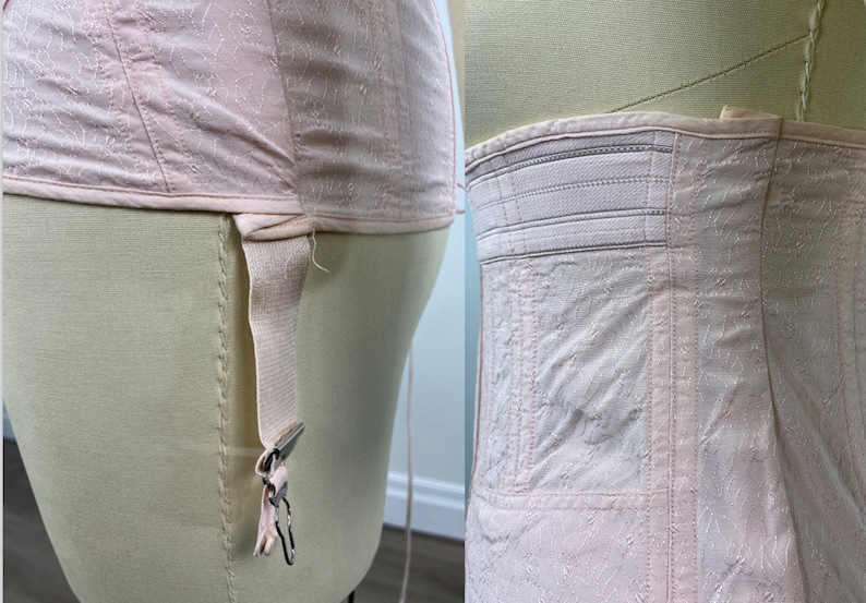 May include: A pink satin corset with a lace pattern and a garter strap on the side. The corset has a white elastic waistband.