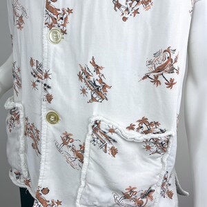 May include: White vest with a brown and black tropical print featuring palm trees and figures. The vest has two front pockets and two large buttons. The edges of the vest and pockets have a frayed design.