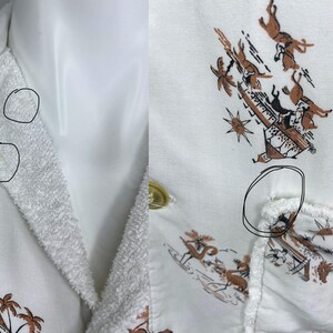 May include: White button-up shirt with a brown and black tropical print featuring palm trees and figures. The collar and lapels have a textured, terry cloth-like appearance. The shirt has a single gold button.