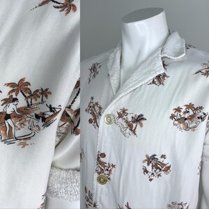 May include: White button-up shirt with a brown and white tropical print featuring palm trees and people surfing. The shirt has short sleeves and a terry cloth collar and cuffs. The shirt is displayed on a white mannequin.