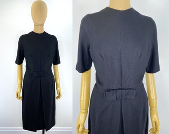 Vestido vintage de lana negra con acento juvenil de la década de 1960 con corpiño arquitectónico, lazo en la cintura y paneles de falda frontal laterales drapeados.