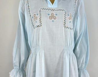 May include: A light blue long-sleeved nightgown featuring a white Peter Pan collar with lace trim. The bodice displays white cutwork embroidery with blue and pink floral accents. The sleeves have elasticized cuffs with white lace trim.