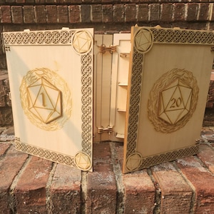 May include: A light-colored wooden dice storage box with two hinged panels. Each panel features a laser-cut icosahedron design, one displaying the number 1 and the other the number 20, surrounded by flame patterns and intricate geometric border detailing.