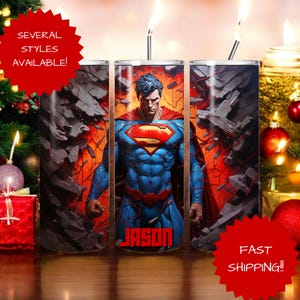 May include: Three stainless steel tumblers featuring a Superman design. The central tumbler displays Superman with a red and yellow logo on his chest, set against a fiery background. The name "JASON" is printed on the tumbler. The text "SEVERAL STYLES AVAILABLE!" and "FAST SHIPPING!!" are also visible.