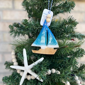 Sailboat Ornament featuring ocean resin art and finished with two wooden beads and blue and white twine.