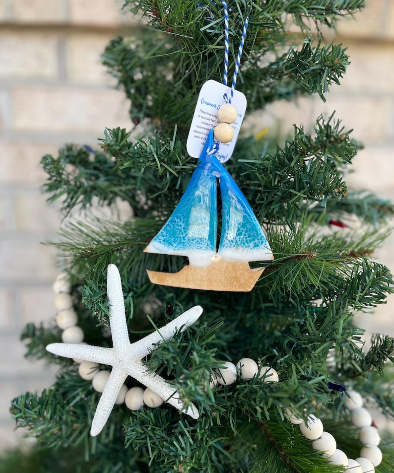 Sailboat Ornament featuring ocean resin art and finished with two wooden beads and blue and white twine.