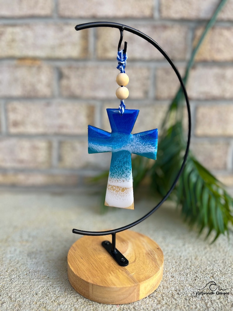 Cross shaped wooden ornament with resin ocean waves on the front on an ornament hanger