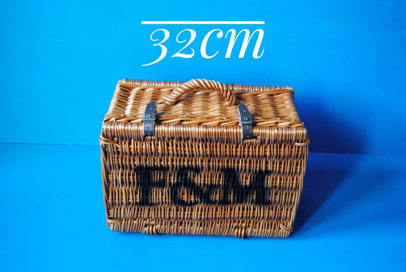 32cm Fortnum and Mason willow picnic basket. The basket is sitting upright, with the Fortnum and Mason logo facing front. The basket has an integrated willow handle, plus a hinged lid that has two leather straps to hold the lid securely in-place