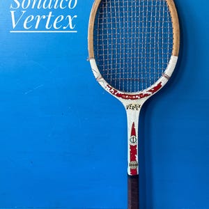 A vintage wooden tennis racket with a natural wood frame, white throat, and red accents. The racket features the text Sondico Vertex, a grid of strings, and a brown leather-wrapped handle. The design includes small circular logos.