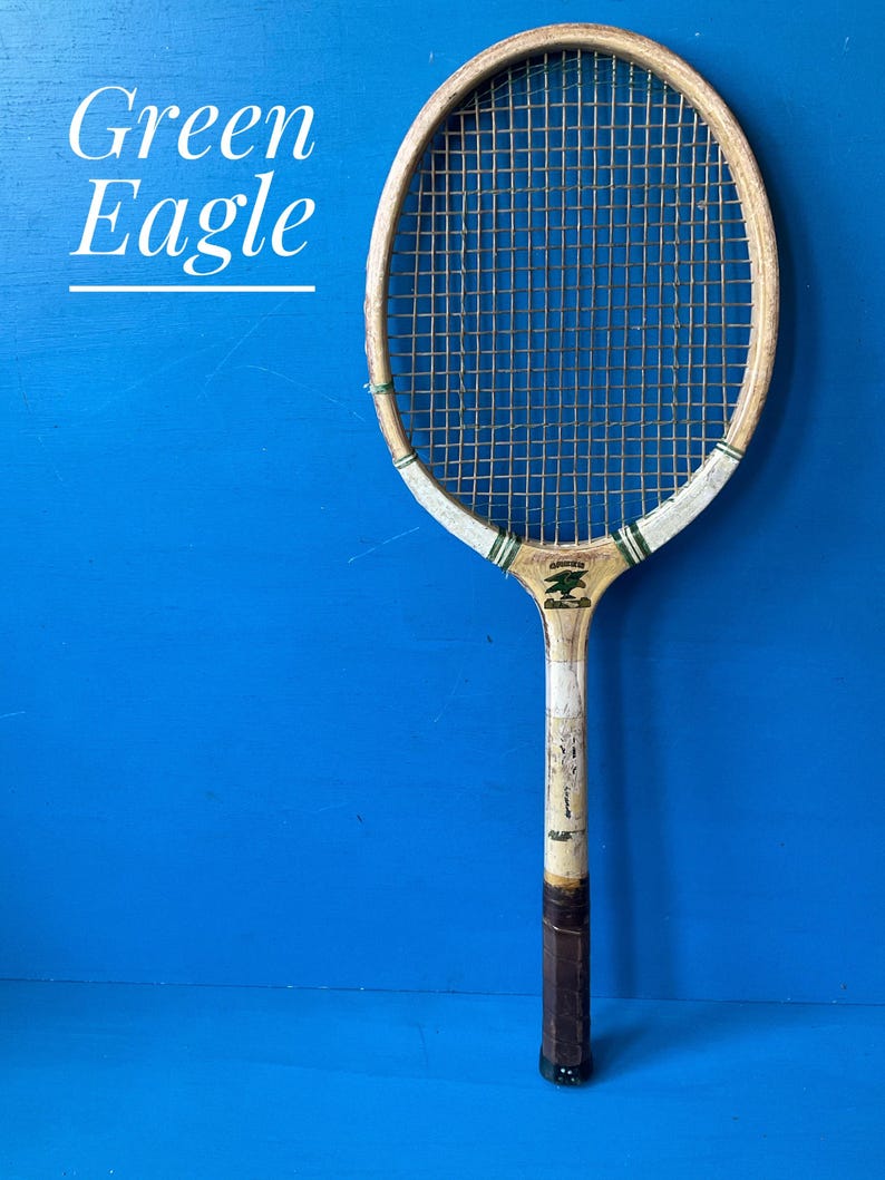 A vintage Green Eagle wooden tennis racket from the 1950s. The racket is predominantly white. There is a picture of a green eagle on the racket face