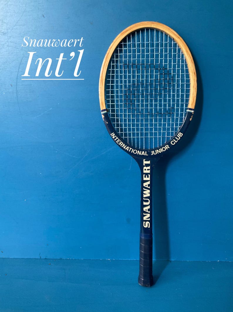 A vintage wooden Snauwaert tennis racket. The racket is has a dark blue handle, with a natural wood head.