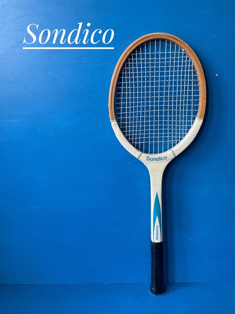 A vintage wooden tennis racket by Sondico. The racket is white, with blue flashes. It has a dark coloured leather hand grip
