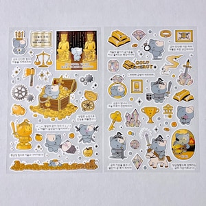 May include: A sheet of stickers featuring cartoon characters and gold-themed illustrations. The stickers include images of treasure chests, gold bars, and a knight. Text in Korean is also present, along with the words "GOLD ENERGY".