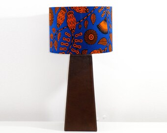 May include: A brown table lamp with a blue and orange patterned lampshade. The lampshade features a floral design with orange flowers and leaves on a blue background.