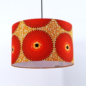 May include: A red and yellow patterned lampshade with a black cord hanging from the ceiling.