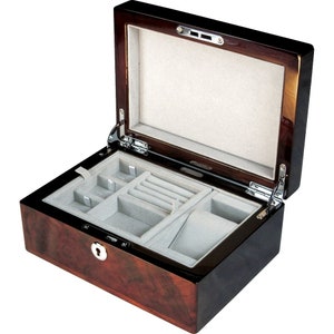 May include: A dark brown wooden jewellery box with a hinged lid and a velvet interior. The box has a lock and key and is divided into compartments for storing jewellery.