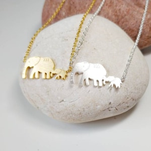 May include: Two silver and gold necklaces with elephant family charms. The charms are of an elephant with a smaller elephant beside it.