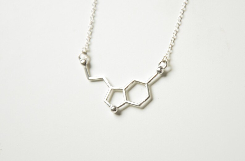 May include: A silver necklace with a pendant shaped like the chemical structure of dopamine.
