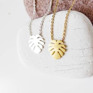Puede incluir: Dos delicados collares con un colgante de hoja de monstera. Uno es de oro y el otro de plata.