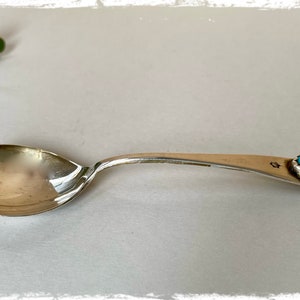 May include: A silver spoon with a turquoise stone set in the handle. The spoon is slightly tarnished and has a simple design.