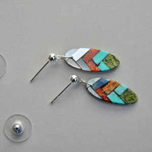 May include: A pair of silver earrings with oval-shaped turquoise, coral, and abalone shell inlay. The earrings have a silver post and a silver ball at the top.