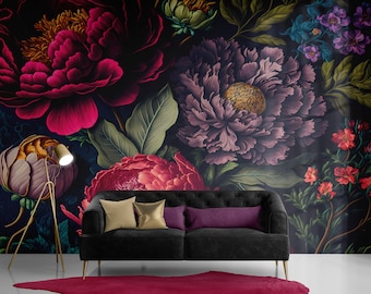 May include: A black velvet sofa with gold legs sits in front of a dark floral wallpaper featuring large pink, purple, and red flowers. The sofa has three pillows, one gold, one gold, and one purple.