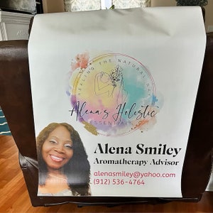 May include: A white banner with a watercolour design featuring a woman with a flower crown. The text "HEALING THE NATURAL WAY" is written in a circle around the woman. Below the circle is the text "Alena's Holistic ESSENTIALS". Below the logo is a photo of a woman with the text "Alena Smiley Aromatherapy Advisor alenasmiley@yahoo.com (912) 536-4764".