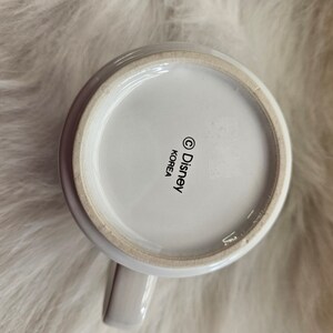 May include: White ceramic mug with a black Disney logo and "Korea" printed on the bottom.