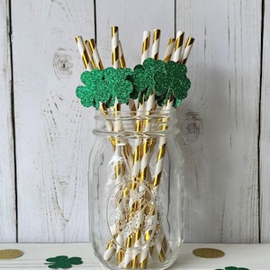 May include: A glass jar filled with gold and white striped paper straws topped with green glitter shamrock cutouts.