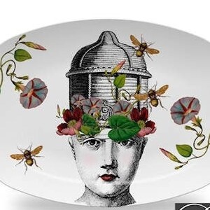 May include: White oval ceramic serving platter with a black and white illustration of a person with a beehive on their head. The person is surrounded by flowers and bees. The platter has the text "Quivering Bee" printed on the bottom.