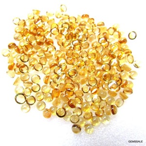 May include: A large pile of round, faceted, yellow gemstones. The gemstones are all approximately the same size and shape.