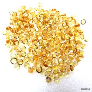May include: A pile of round, faceted, yellow gemstones. The gemstones are approximately 4mm in diameter and have a smooth, polished finish.