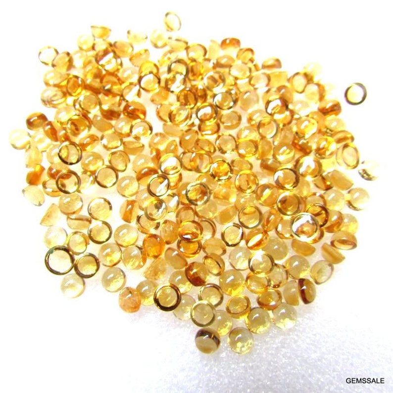 May include: A pile of round, faceted, yellow gemstones. The gemstones are approximately 4mm in diameter and have a smooth, polished finish.