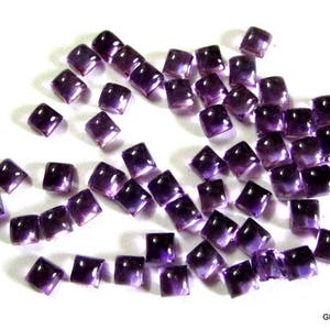 May include: A collection of purple square-shaped amethyst gemstones. The gemstones are faceted and have a shiny finish.