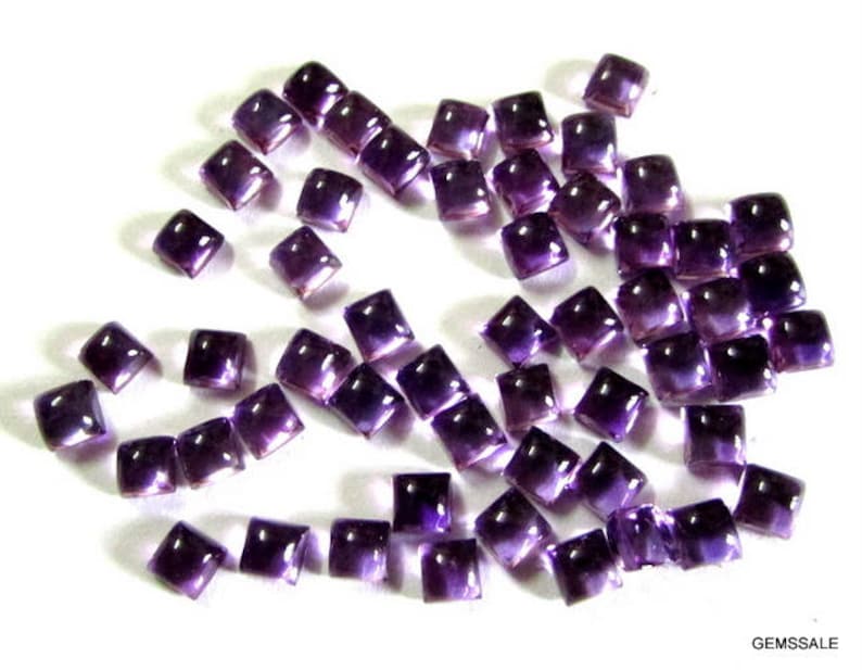 May include: A collection of purple square-shaped amethyst gemstones. The gemstones are faceted and have a shiny finish.