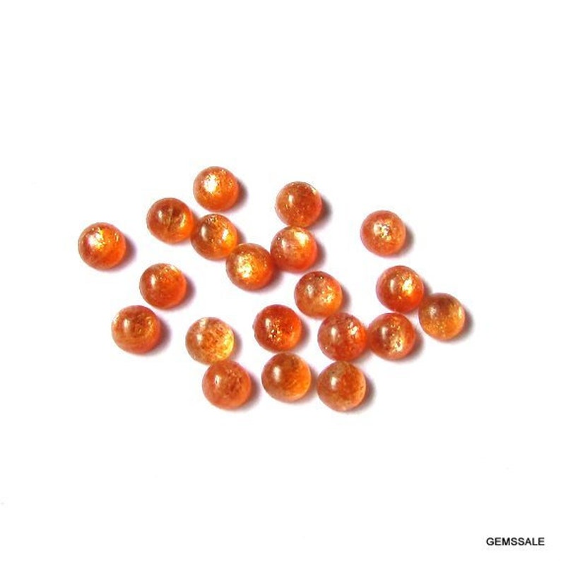 May include: A collection of 17 round, orange sunstone cabochons. The stones are smooth and polished, with a slight shimmer.