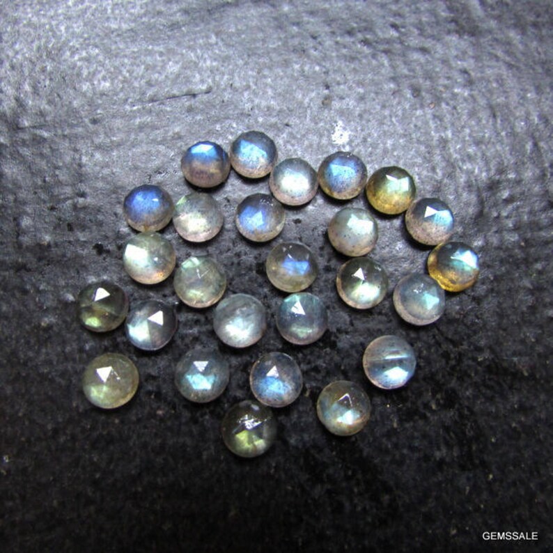 Puede incluir: Una colecci&oacute;n de 20 cabujones de labradorita, piedras preciosas iridiscentes. Las piedras son redondas y tienen un corte facetado. Son de una mezcla de colores azul claro, gris y verde.