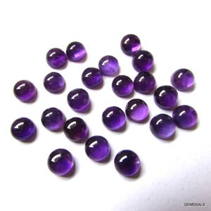 May include: A collection of 20 round, purple amethyst cabochons. The cabochons are smooth and polished, with a slight variation in color and size.