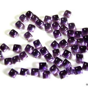 May include: A collection of purple amethyst gemstone cabochons, cut into square shapes. The stones are faceted and have a smooth, polished finish.