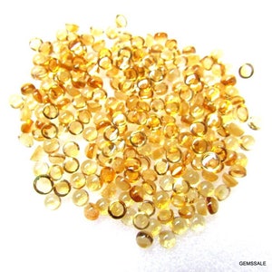May include: A large pile of round, faceted, translucent, golden yellow gemstones. The gemstones are approximately 4mm in diameter and have a smooth, polished finish.