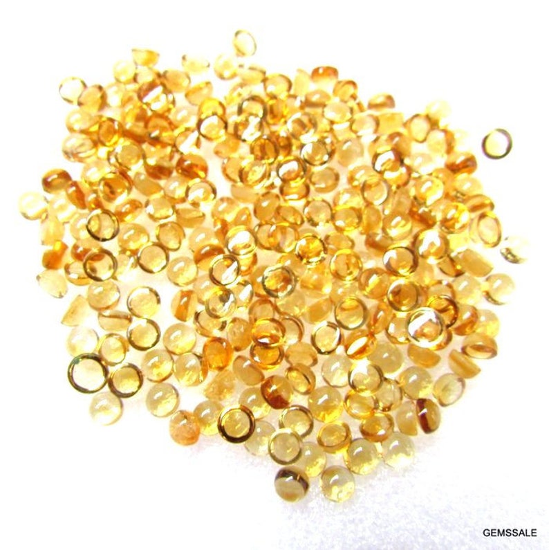 May include: A large pile of round, faceted, translucent, golden yellow gemstones. The gemstones are approximately 4mm in diameter and have a smooth, polished finish.