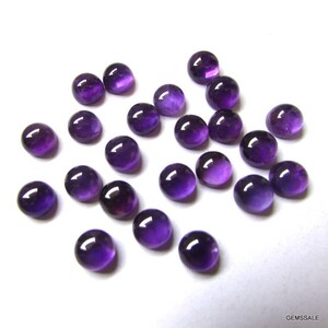 May include: A collection of 20 round, purple amethyst cabochons. The cabochons are smooth and polished, with a slight variation in size and shade.