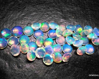 Pode incluir: Uma coleção de gemas de opala iridescente, cada uma com um padrão único de cores azuis, verdes e brancas. As gemas são redondas e lisas, e estão dispostas em uma pilha solta.
