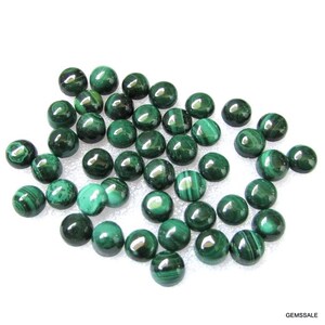 May include: A collection of round, green malachite cabochons. The cabochons are smooth and polished, with a variety of patterns and colors.