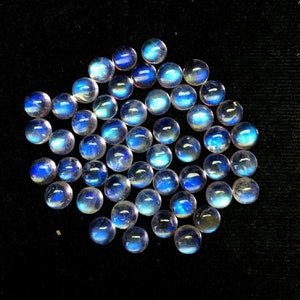 Puede incluir: Una colecci&oacute;n de cabujones redondos de piedra lunar iridiscente en varios tonos de azul y blanco.