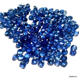 Pu&ograve; includere: Un grande mucchio di pietre preziose di zaffiro blu sfaccettate. Le pietre preziose sono rotonde e hanno una finitura liscia e lucida.