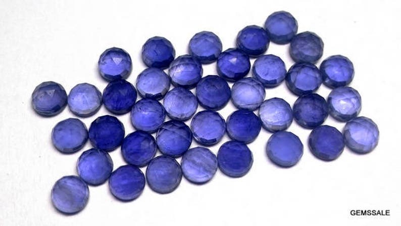 May include: A collection of 25 faceted round blue gemstones. The gemstones are approximately 6mm in diameter and have a variety of shades of blue.