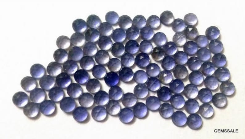 May include: A collection of 50 round, faceted, purple amethyst gemstones. The stones are approximately 6mm in diameter and have a smooth, polished finish.